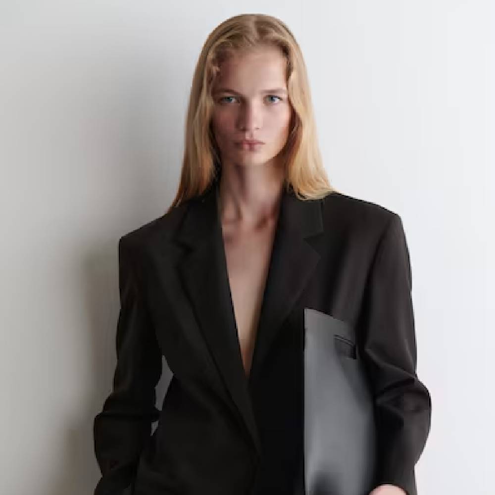 A female model wearing a dark brown blazer from COS.