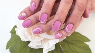 Scattered daisy nail art on pink nails