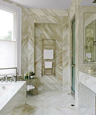 Small bathroom tile ideas showing marble floor and wall tiles with a gold radiator