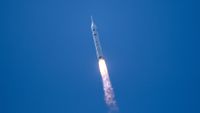 a white rocket launches into a cloudless blue sky