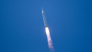 a white rocket launches into a cloudless blue sky