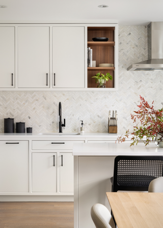 A bright, kitchen with white cabinets and marble tiles