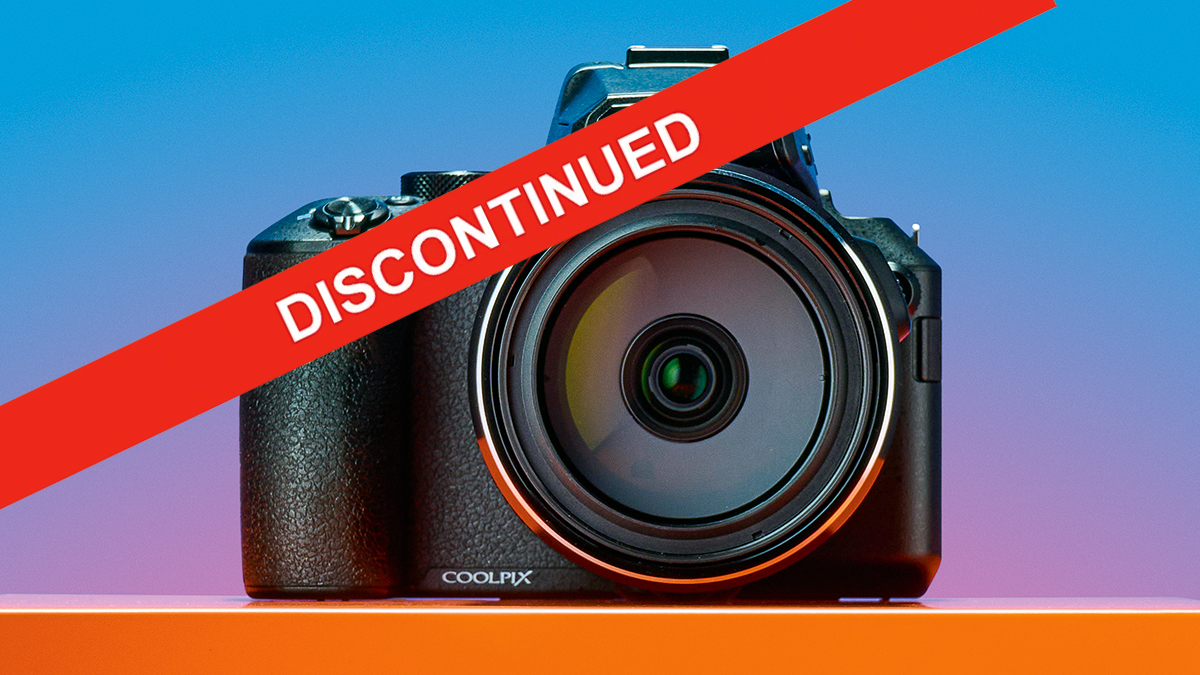 Front view of a Nikon Coolpix 950 camera with a red "DISCONTINUED" banner across it, on an orange surface with a gradient background.