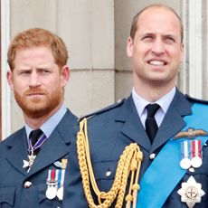 Prince Harry looks at Prince William on the Buckingham Palace balcony as both wear military uniforms