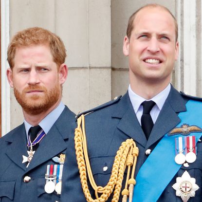 Prince Harry looks at Prince William on the Buckingham Palace balcony as both wear military uniforms