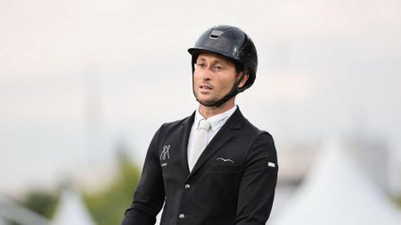British showjumper Adrian Whiteway wearing a black show jacket and riding hat with a white shirt and tie.
