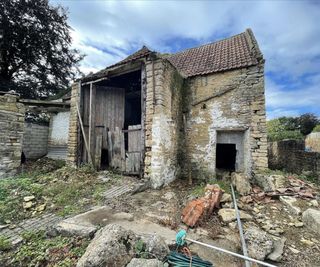 A stone barn building with two large wooden front doors