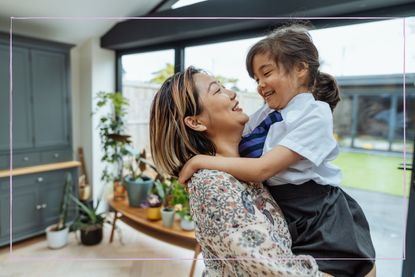 Mum holding her daughter who is wearing school uniform 