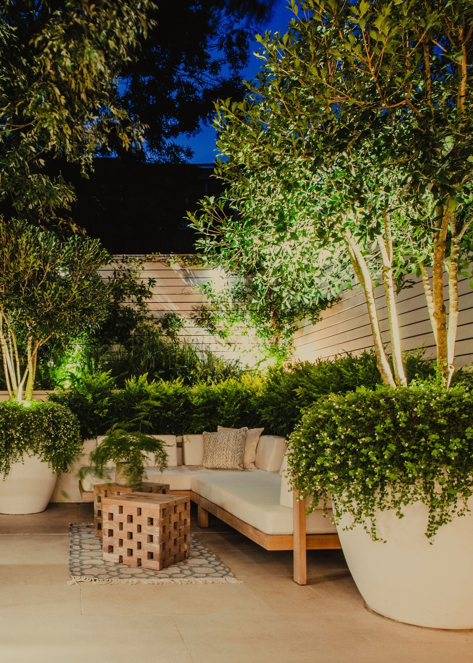 patio with huge white pots, pale slabs, pale fencing and light-colored sofa