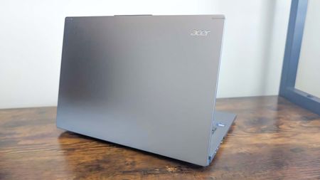 Acer Aspire 14 AI on a wooden desk and facing away to show the lid. 