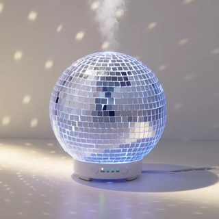 A glowing disco ball essential oil diffuser with light reflecting on background