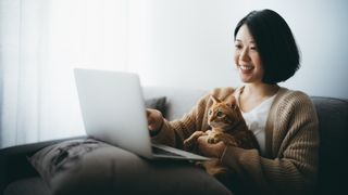 Woman browsing the Amazon Prime Day cat deals on her laptop with ginger cat on her lap