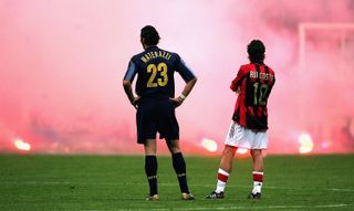 Inter's Marco Materazzi and AC Milan's Rui Costa watch on as Inter fans throw flares onto the pitch in a Champions League quarter-final match at San Siro in 2005.