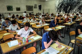 A hall full of students sitting at desks taking an exam