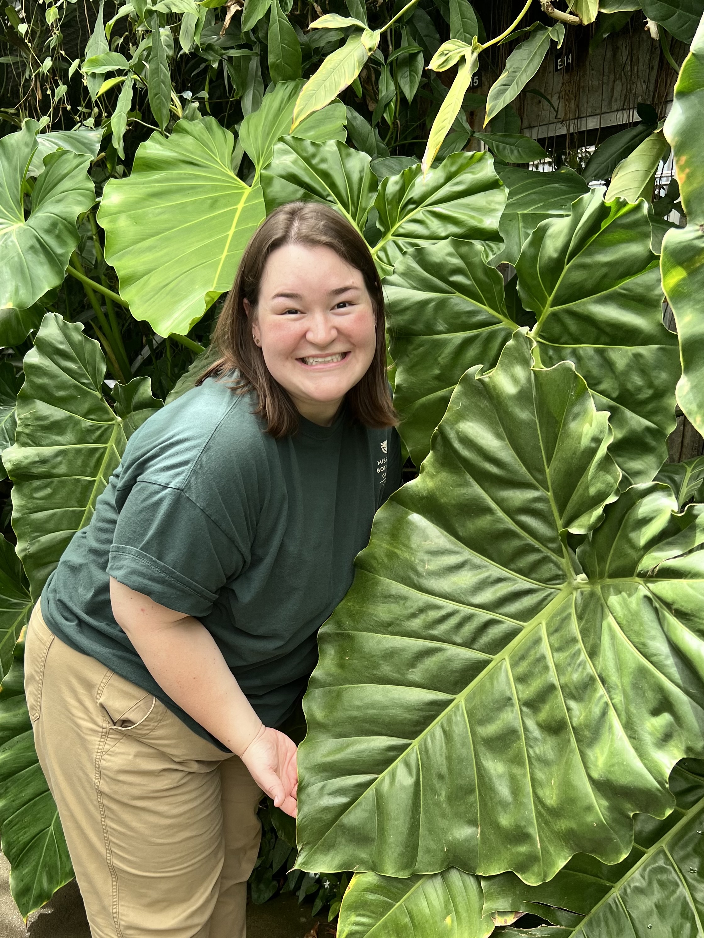 young woman in front of plant with large leaves