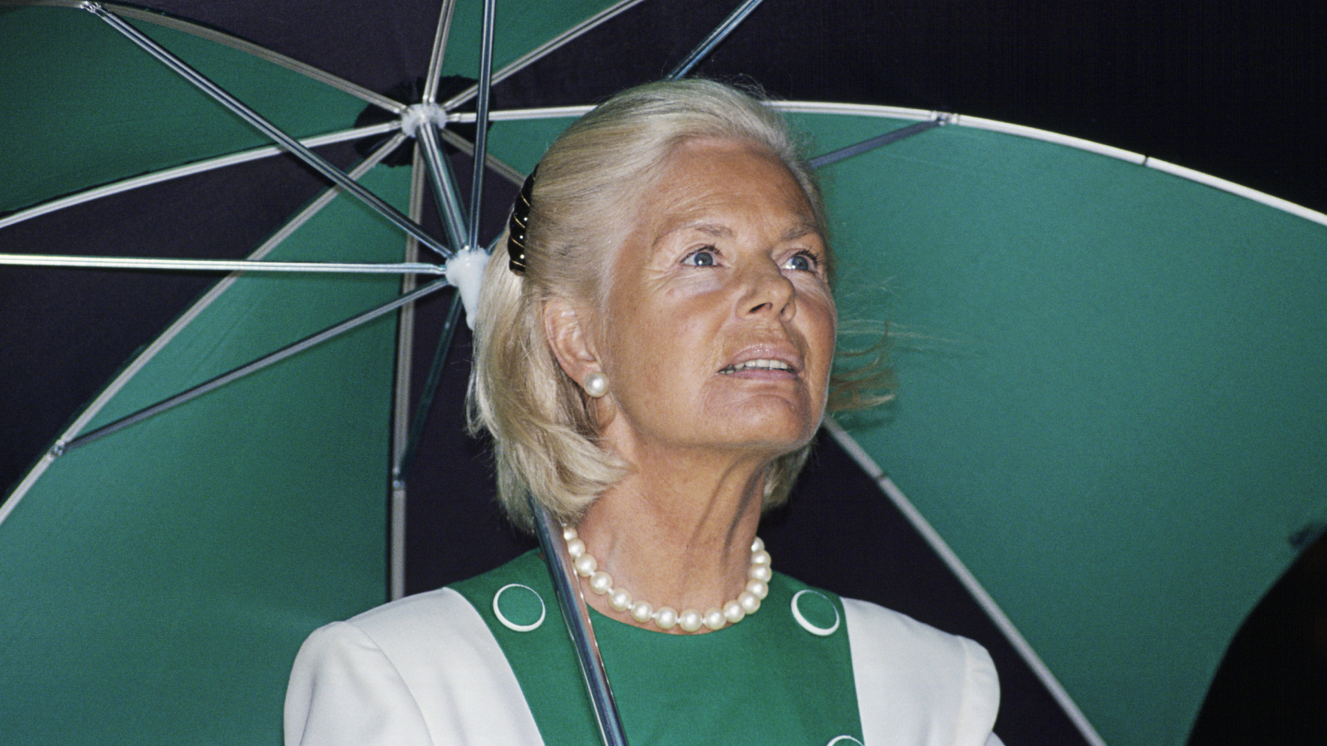 The Duchess of Kent carries a green and black umbrella which coordinates with her white and green dress