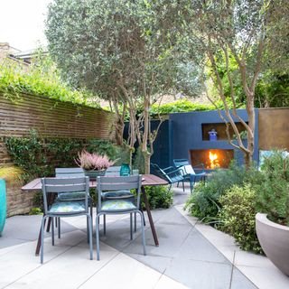 garden with blue painted wall and fireplace table and chairs