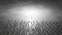 from high above a flat grey expanse, a single silhoutted figure stands in the center, on the bottom half of the image, dozens of other small silhouetted figures face the central one. Their shadows fall downward.