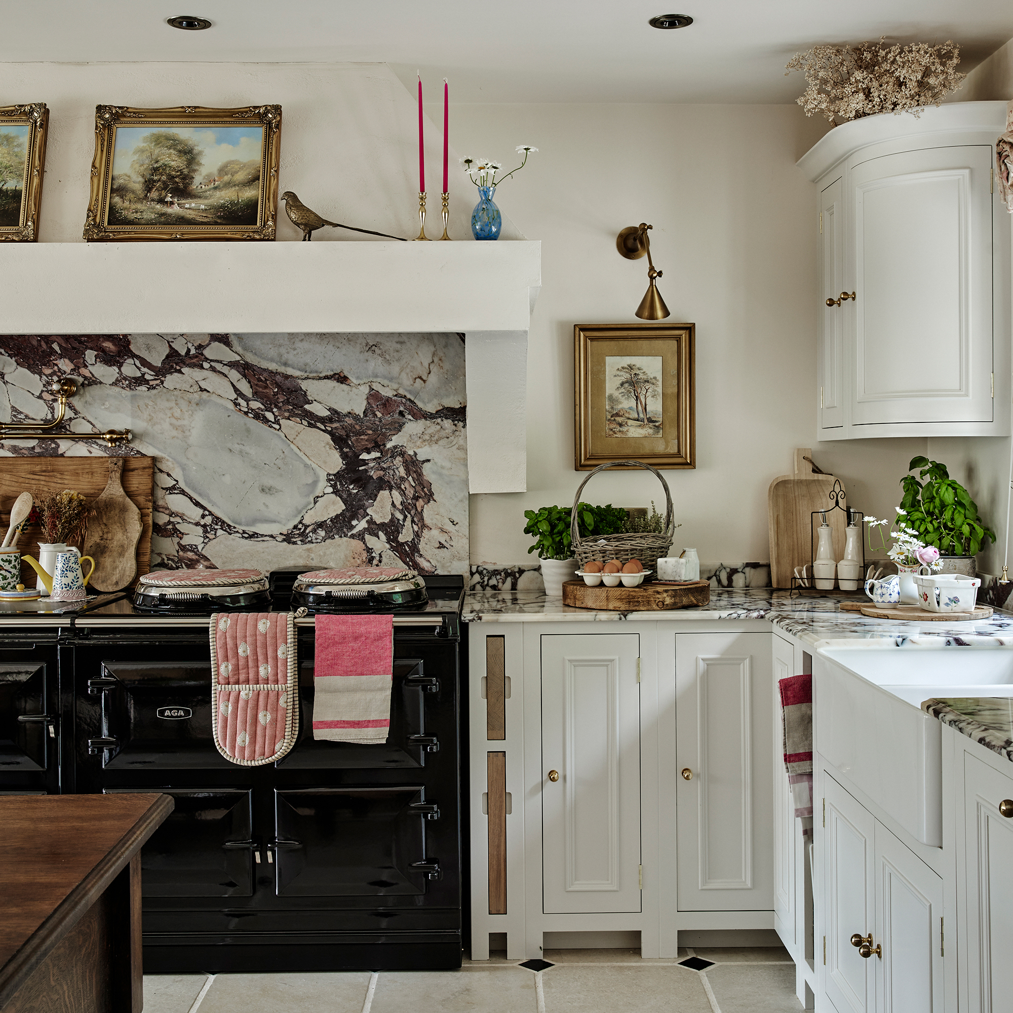 neutral country style kitchen with black range cooker and vintage paintings