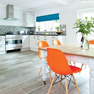 kitchen with white wall and table with orange chairs