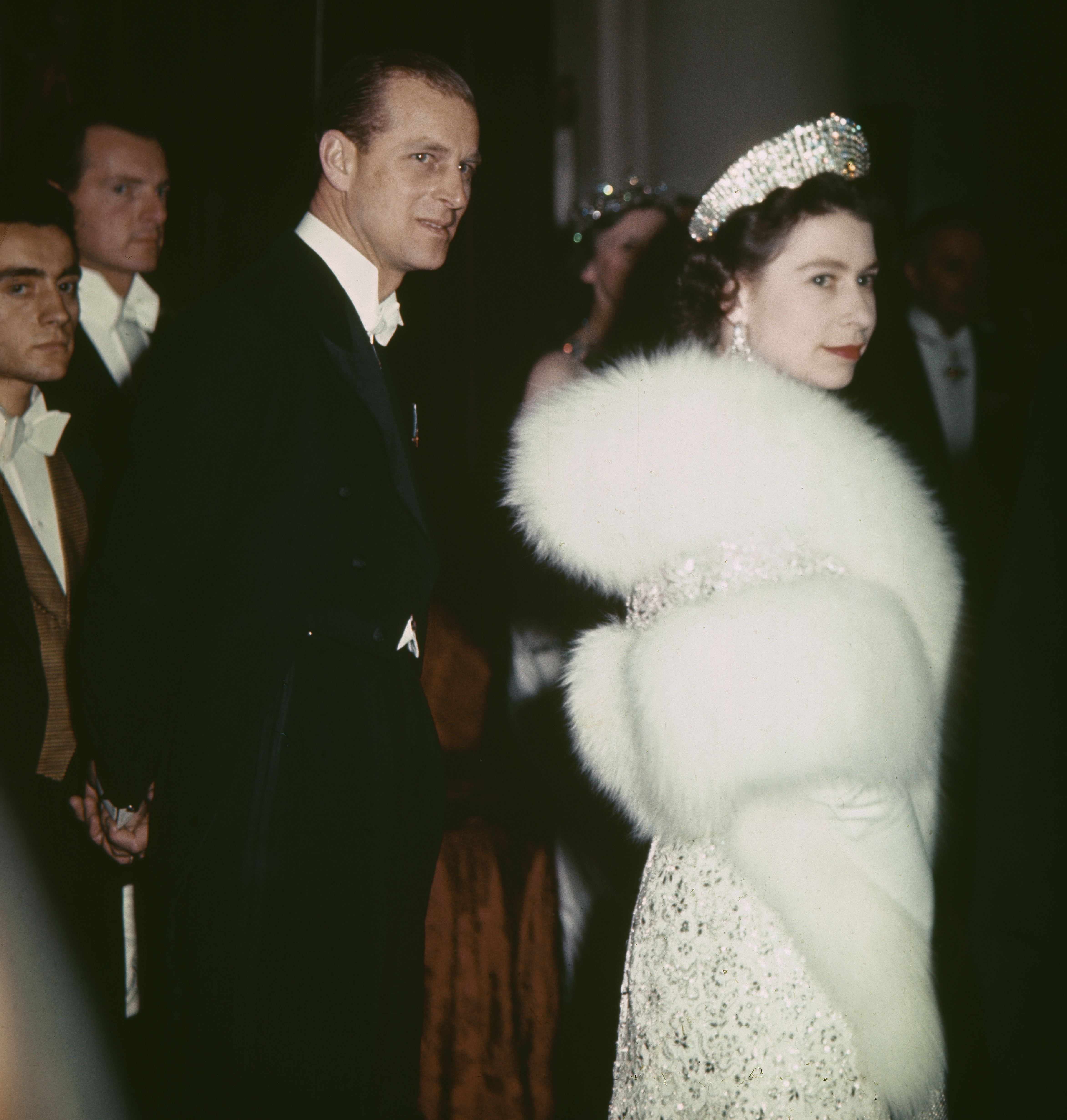 Queen Elizabeth in a tiara and fur standing next to Prince Philip