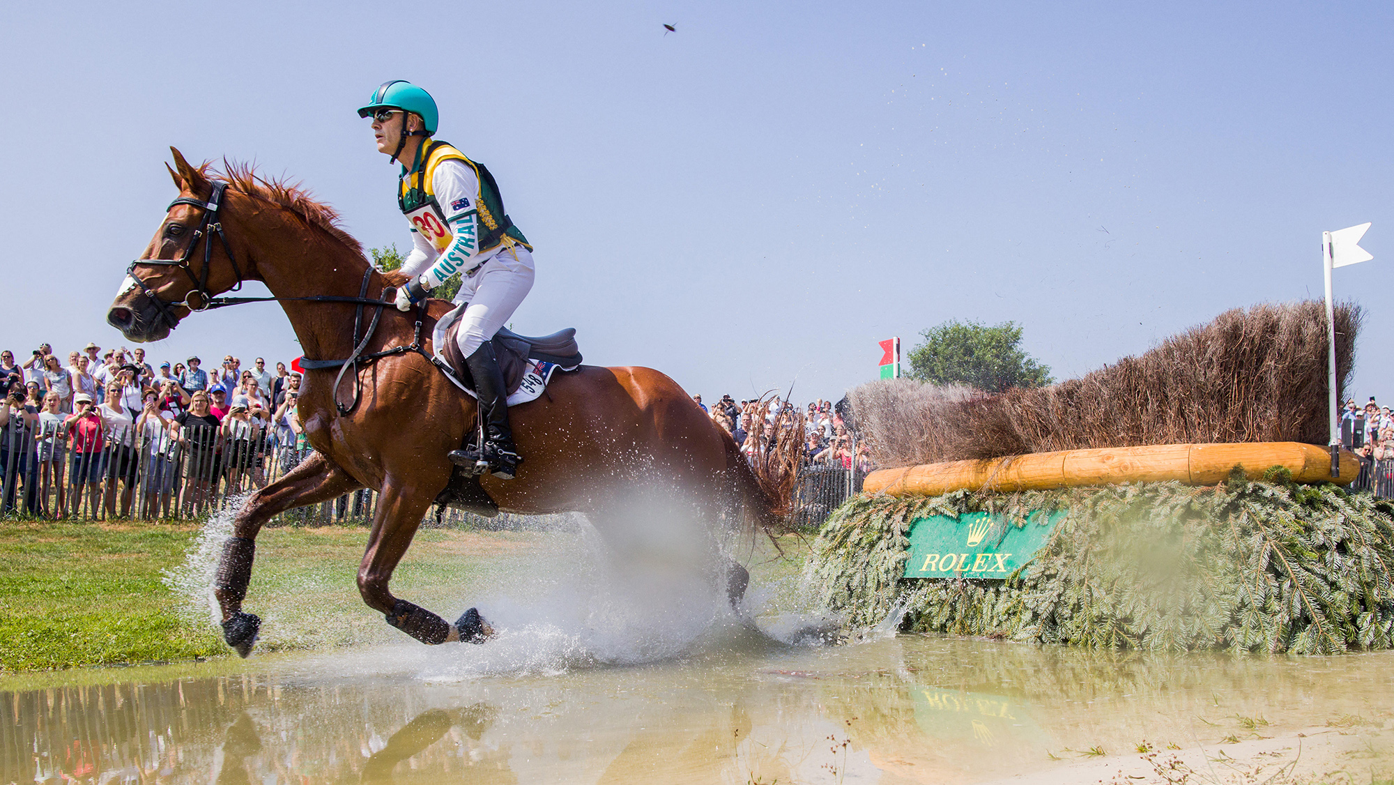 Andrew Hoy and Vassily De Lasos canter away through the water after jumping a large brush fence at Aachen