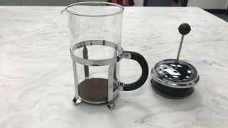 A french press with unsaturated coffee grounds in the bottom