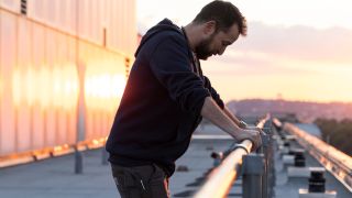 Noah Wyle dramatically leans on a railing at sunrise in The Pitt S1 E1 - "7:00 AM."