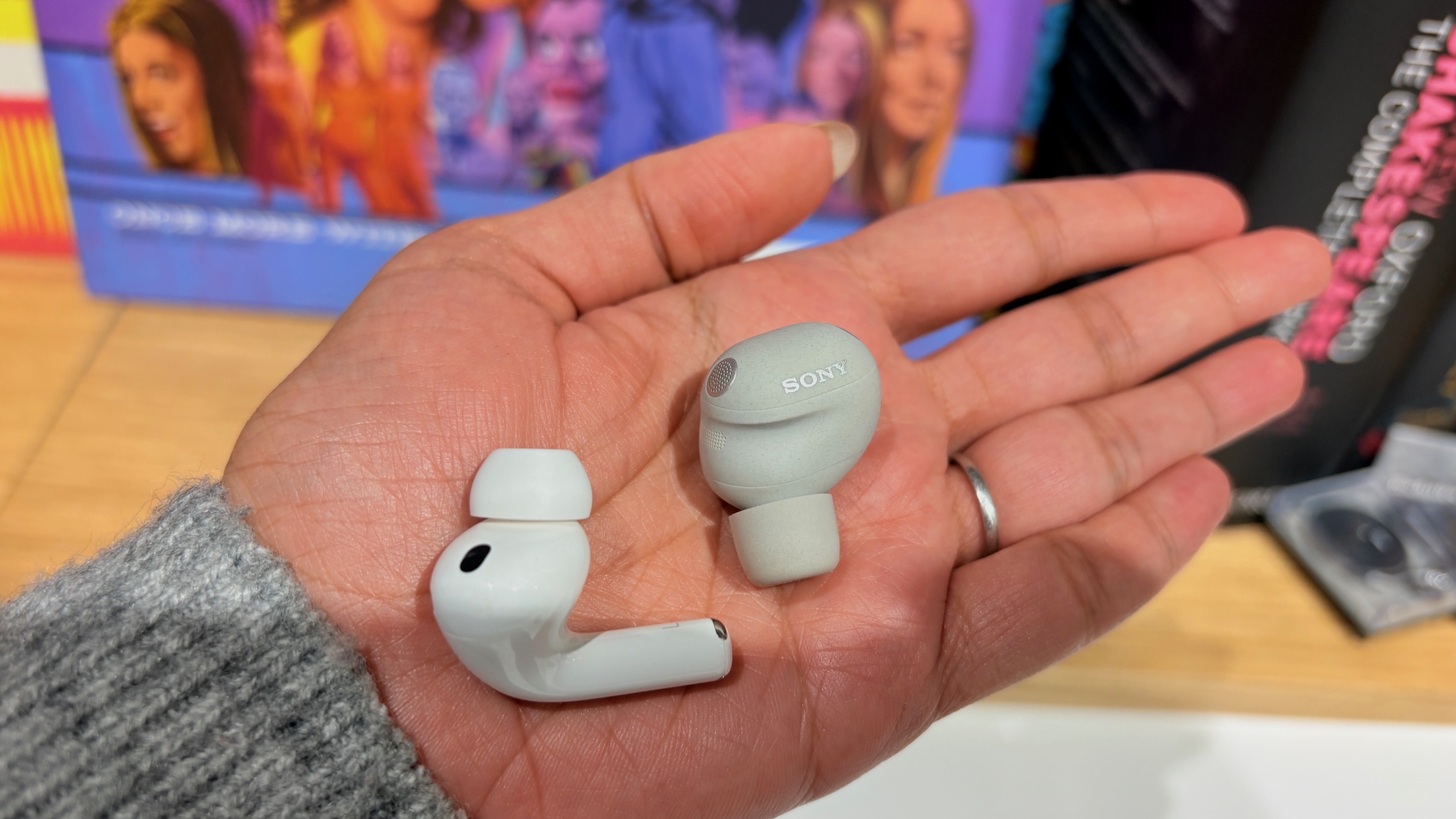 A Sony WF-1000XM6 and an Apple AirPods Pro 3 earbud held in the palm of a hand.