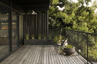 A balcony with gray decking and a modern chair