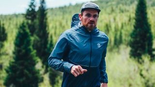 Man running in rain wearing cap and waterproof jacket