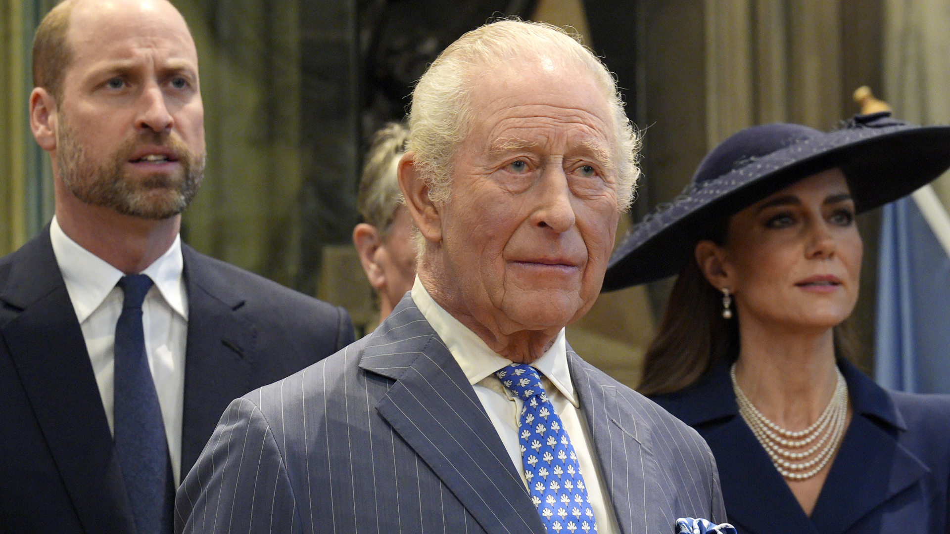 King Charles wears a pinstripe suit and has white gray hair and bloodshot eyes