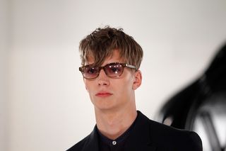 male model wearing black shirt, glasses and long textured fringe
