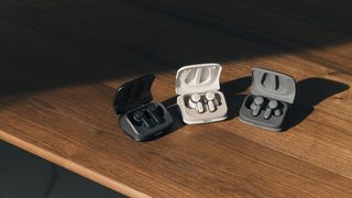 Three pairs of Audio-Technica ATH-TWX7WH wireless earbuds on a wooden table