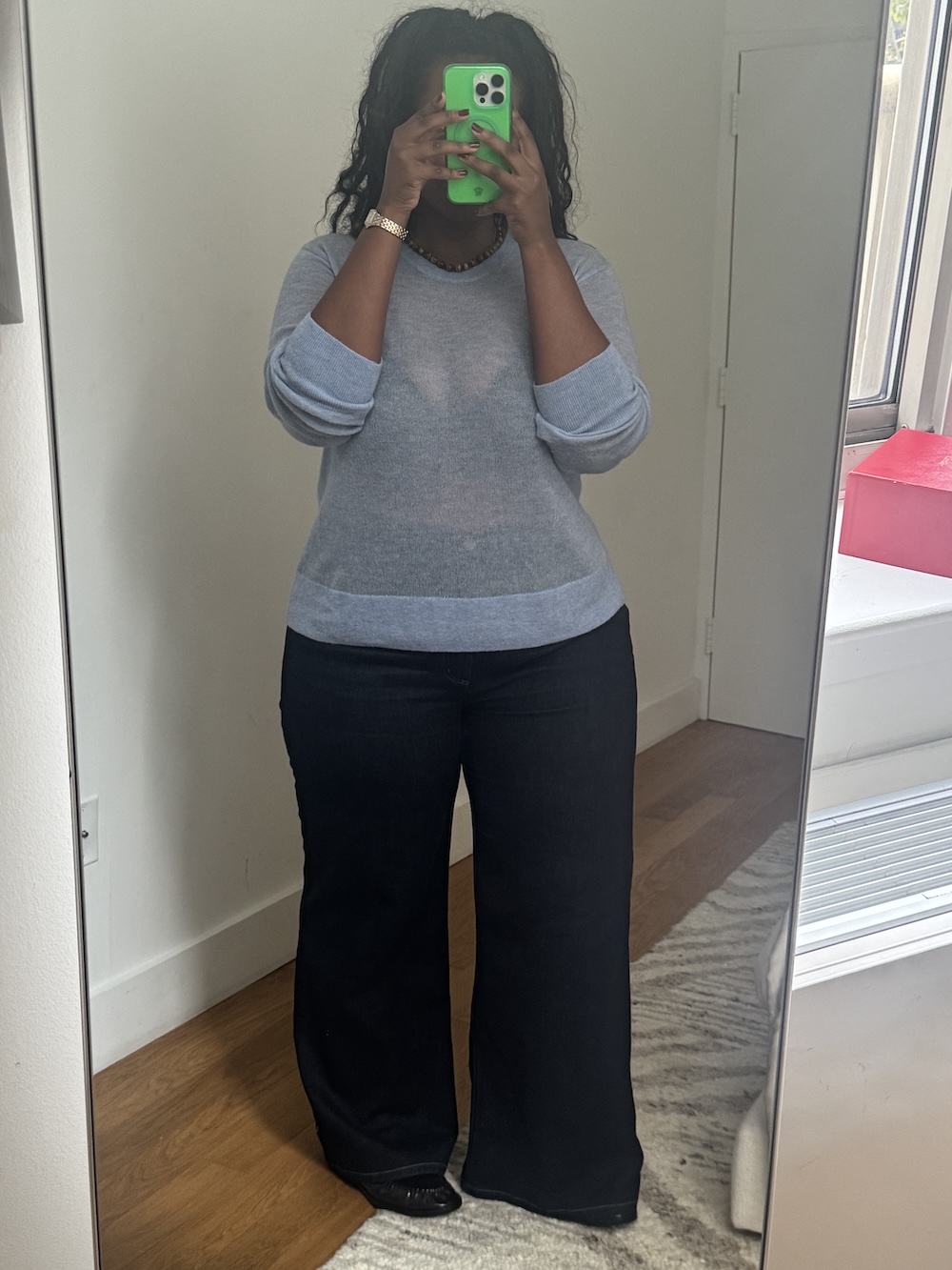 Tariro Makoni wears a blue sweater from Everlane and wide leg pants