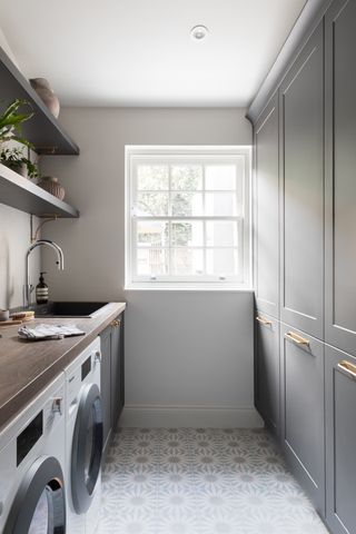 Narrow utility room ideas showing grey cabinets and ornate tiled flooring