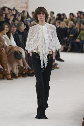 Chloé model on runway wearing white frilly blouse and jeans