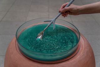 performer stirs green liquid with long spoon