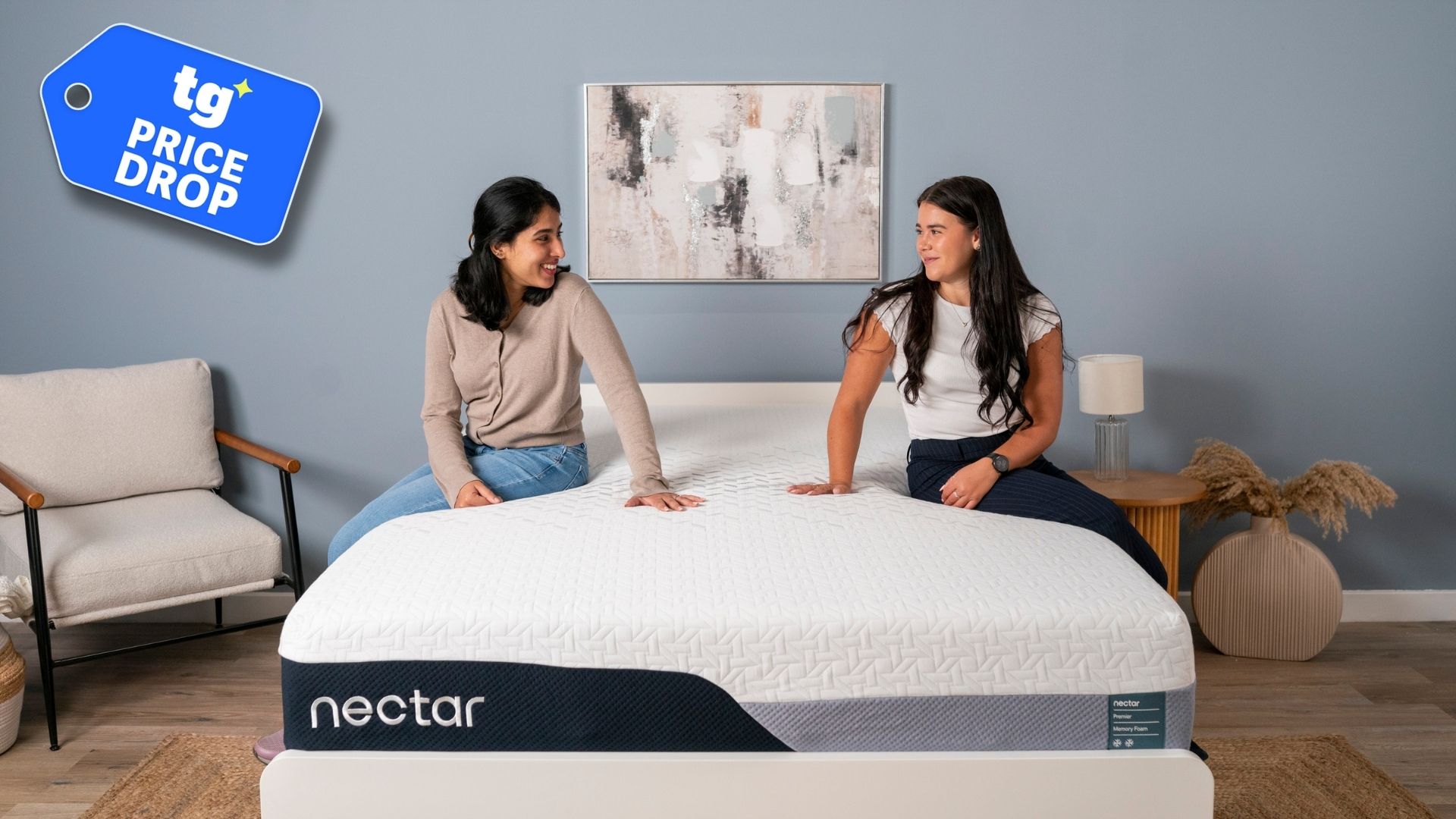 Two women sit on the edges of the Nectar Premier Memory Foam Mattress in a modern bedroom. 