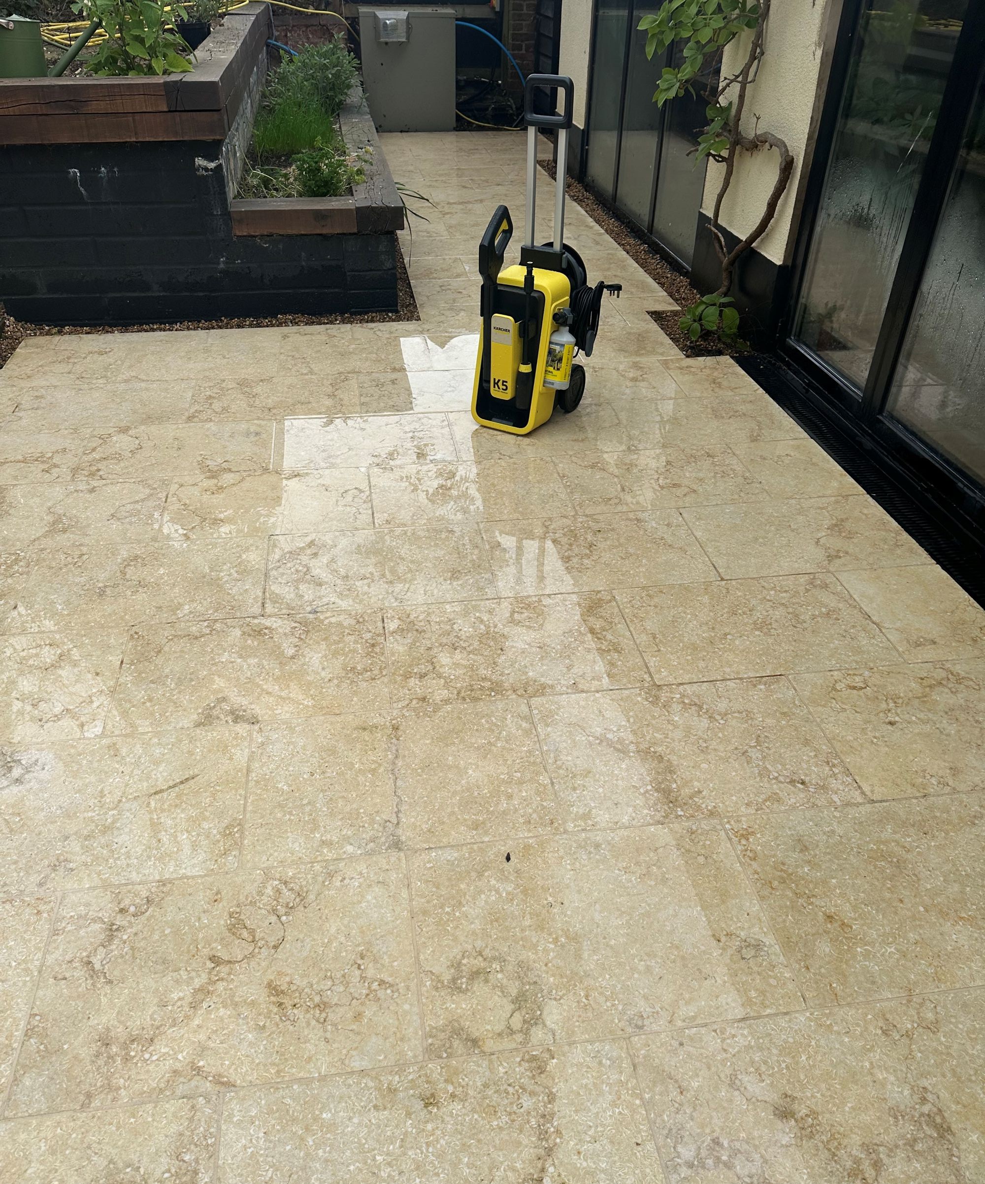 A yellow Karcher K5 Comfort Premium pressure washer on a cream limestone patio
