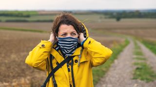 Woman putting on neck gaiter in countryside