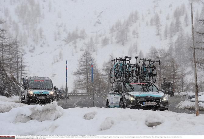 Team cars drive through the snow in Romandie