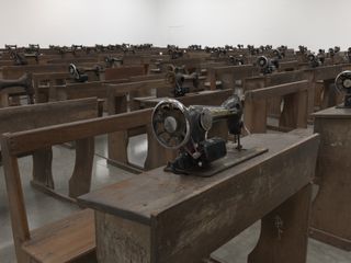 Close up of wooden desks and tables with sewing machines, installation at White Cube, by Ibrahim Mahama