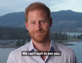 Prince Harry standing in front of a mountain backdrop