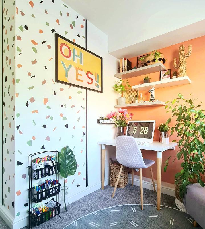 fun home office with geometric shape colorful wallpaper, an orange wall with a white desk against it, lots of plants, and an 'Oh Yes!' print