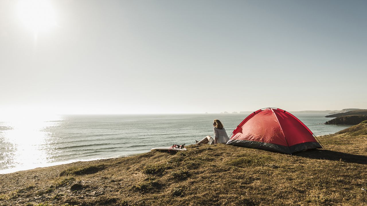 Campsites by the beach: a woman overlooking the sea from a campsite on the beach