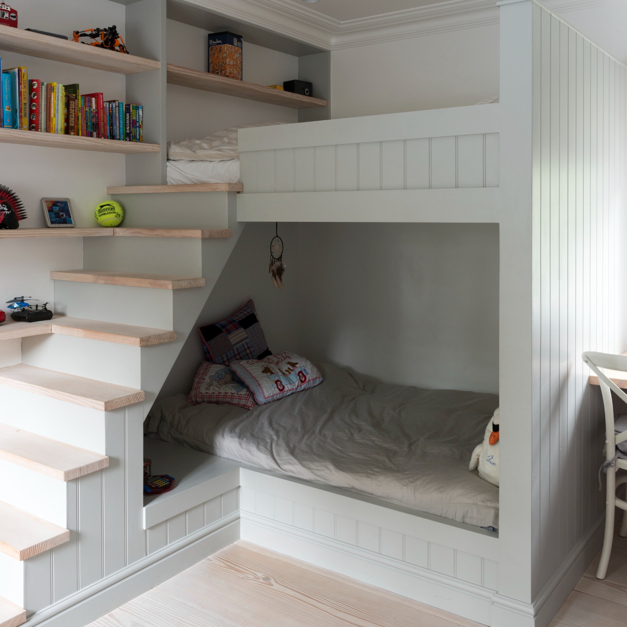 A teenager's bedroom with built-in bunk beds, stairs and display shelves