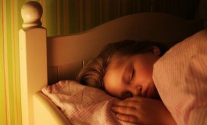 A young girl sleeps with a light on