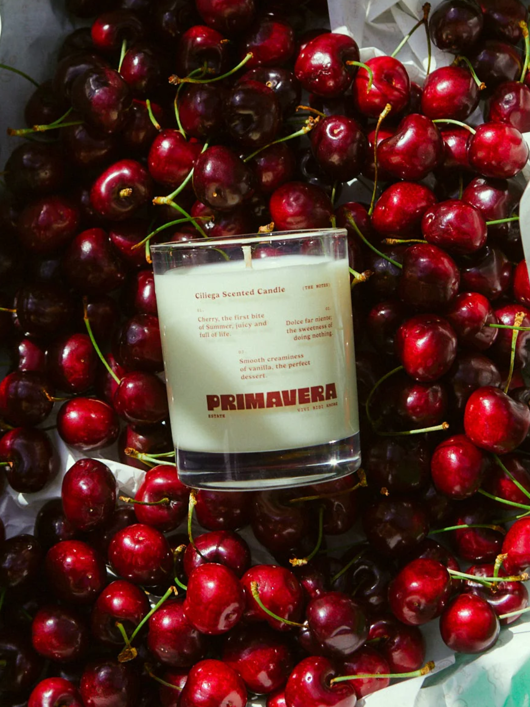 A glass candle nestled into a crate of cherries from Earl of East