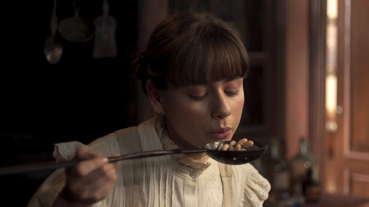 Azul Guaita's Tita blowing on a ladel with beans in it in Like Water For Chocolate Season 2